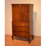 A mahogany cupboard on chest, with two panelled doors above three graduated drawers,