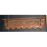 A French oak hat and coat wall mounting shelf, with seven gilt metal mask hooks,