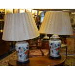 A pair of Chinese type ceramic vase lamps with shades, decorated with floral panels on white ground,