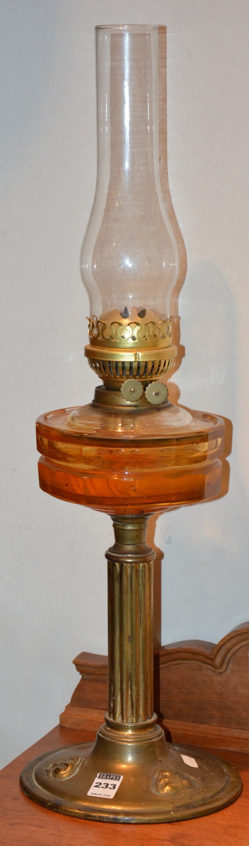 A late Victorian brass oil lamp, with glass funnel and amber coloured glass reservoir,