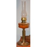 A late Victorian brass oil lamp, with glass funnel and amber coloured glass reservoir,