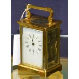 A brass carriage clock, with white enamel dial and carry handle,