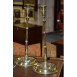 A pair of tall brass candlesticks, raised on tapering stem and circular foot,