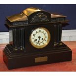 A Victorian black slate mantel clock, with cream enamel dial above presentation label,