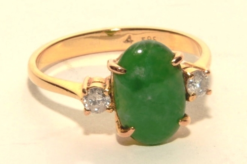 A 14ct gold jade and diamond ring, the central oval green jade cabochon (approx 1.