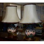 A pair of Moorcroft vase table lamps with shades, with tube line decoration on pink, yellow, green,