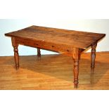 A late 19th century farmhouse pine kitchen table, with plank top, raised on spindle supports,