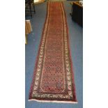 An Iranian hand made runner, the allover foliate motif over red ground,