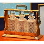 An Edwardian oak cased three bottle Tantalus, with plated mounts (opens but no key),