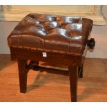 An adjustable piano stool, with brown leather top,