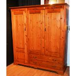 A modern pine wardrobe, with three panelled doors above two long drawers, raised on plinth base,