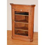 A Victorian pine corner cabinet, with glazed door enclosing shelved interior,