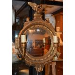 A Regency style gilt convex wall mirror, decorated with eagle surmount and two candle sconces,