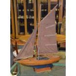 A vintage wooden pond yacht, with brown fabric masts,
