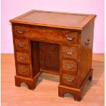 A reproduction figured walnut kneelhole desk in the Georgian style,