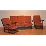 An Ercol sofa and twin armchair suite, with red loose cushion seats and backs,