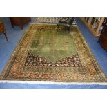 A Persian carpet, decorated with three long floral motifs on green ground, with gold floral border,