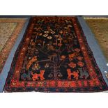 A Persian rug, the central panel depicting animals in foliage over navy ground,