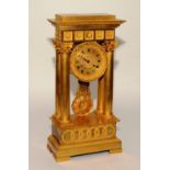 A 19th century French empire ormolu portico mantel clock, decorated with five floral roundels,
