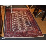 An Eastern rug, the central panel decorated with multiple red guls over white ground,