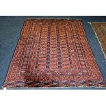 An Eastern rug, the central panel decorated with multiple red guls on navy ground,