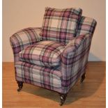 A tartan upholstered armchair, raised on turned mahogany supports with brass castors,