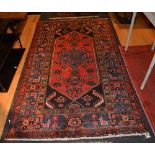 An Eastern rug, the central blue medallion on red ground, surmounted by allover foliate ground,