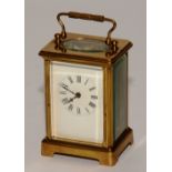 A brass carriage clock, with handle above enamel dial with Roman numerals,