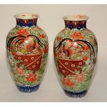 A pair of 19th century Japanese Imari pottery vases, decorated with panels of birds in foliage,