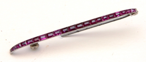 A Cartier white metal and ruby bar brooch, the 21 graduated rubies within channel setting,