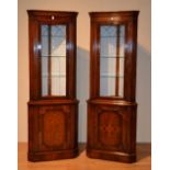 A pair of good reproduction walnut corner cabinets, with glazed door, enclosing glass shelves,