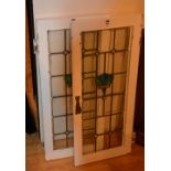 A pair of stained leaded glass windows, within painted white frames,