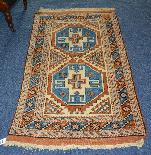 An Eastern rug, the two central geometric medallions on blue and white ground,
