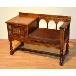 A Priory style oak telephone seat in the form of a hall bench,