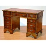 A reproduction walnut kneehole desk, with red tooled leather inset to top,