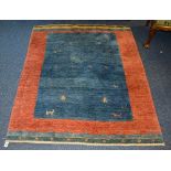 An Eastern rug, of plain design with central blue panel decorated with motifs of men and animals,