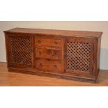 A hardwood sideboard, with three drawers, flanked by a lattice carved door,