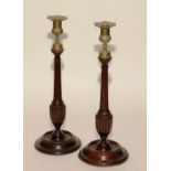 A pair of late 18th/early 19th century George III turned mahogany candlesticks, with brass tops,