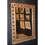 A late 19th/early 20th century giltwood wall mirror, decorated with scrolls, with later backing,