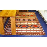 An Afghan rug, with three horizontal panels of geometric designs in red, white, orange and blue,