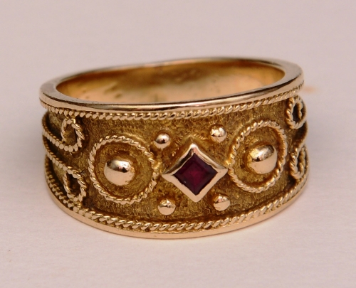 An unmarked gold and ruby ring, the central diamond shaped ruby to centre,