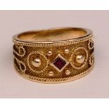 An unmarked gold and ruby ring, the central diamond shaped ruby to centre,