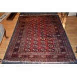 An Eastern rug, the central panel decorated with multiple guls on red ground,