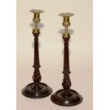 A pair of late 18th/early 19th century George III turned mahogany candlesticks, with brass tops,