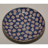 A Chinese circular plate, decorated with red and yellow flowers on blue ground,