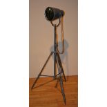 A floor standing painted metal spotlight, used as a mirror, raised on tripod supports,