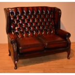 A Queen Anne style ox blood leather two seater wing back settee, with button back,