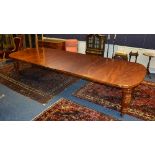 A Victorian style mahogany extending dining table, with four leaves, raised on baluster supports,