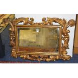 An early 20th century gilt mirror, the frame ornately decorated in foliate gesso relief,