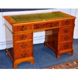 A reproduction yew wood kneehole desk, with tooled green and gilded leather inset to the top,